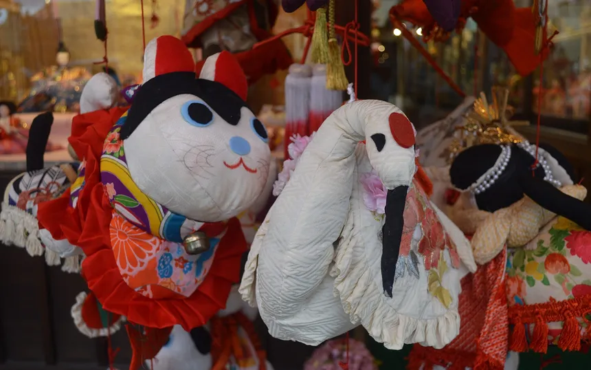 Cloth figures on a sagemon: a cat, a crane and a baby