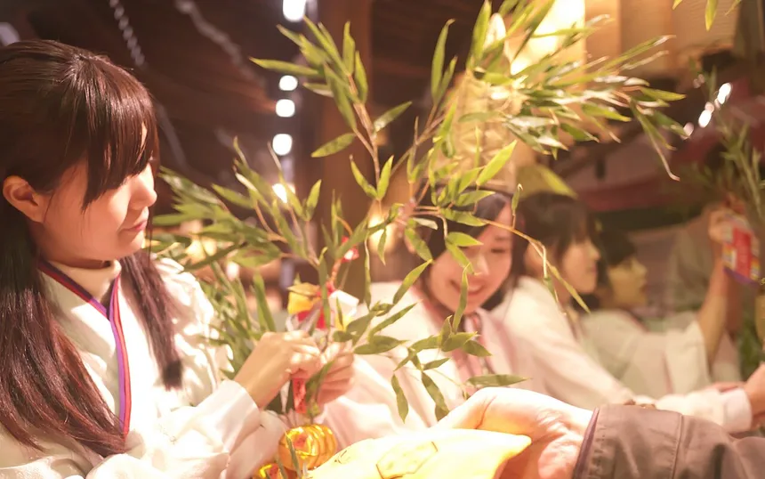 A shrine maiden tying charms onto a bamboo branch at Toka Ebisu