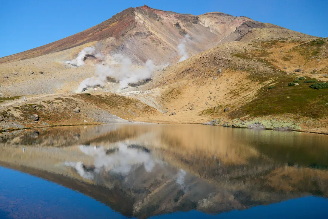 Asahidake and its steam vents reflected in Sugatami Pond in early October
