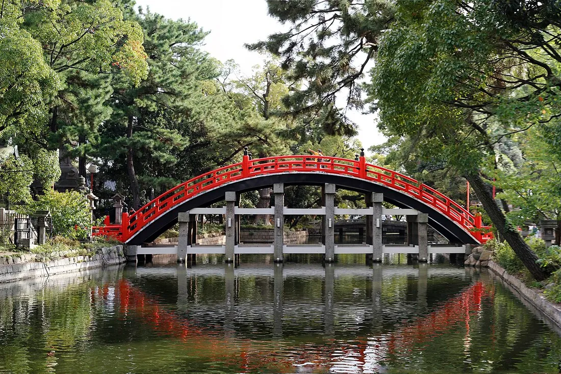 The red arched Sorihashi bridge of Sumiyoshi Taisha reflected in its pond; the moon-viewing rite is held on this bridge