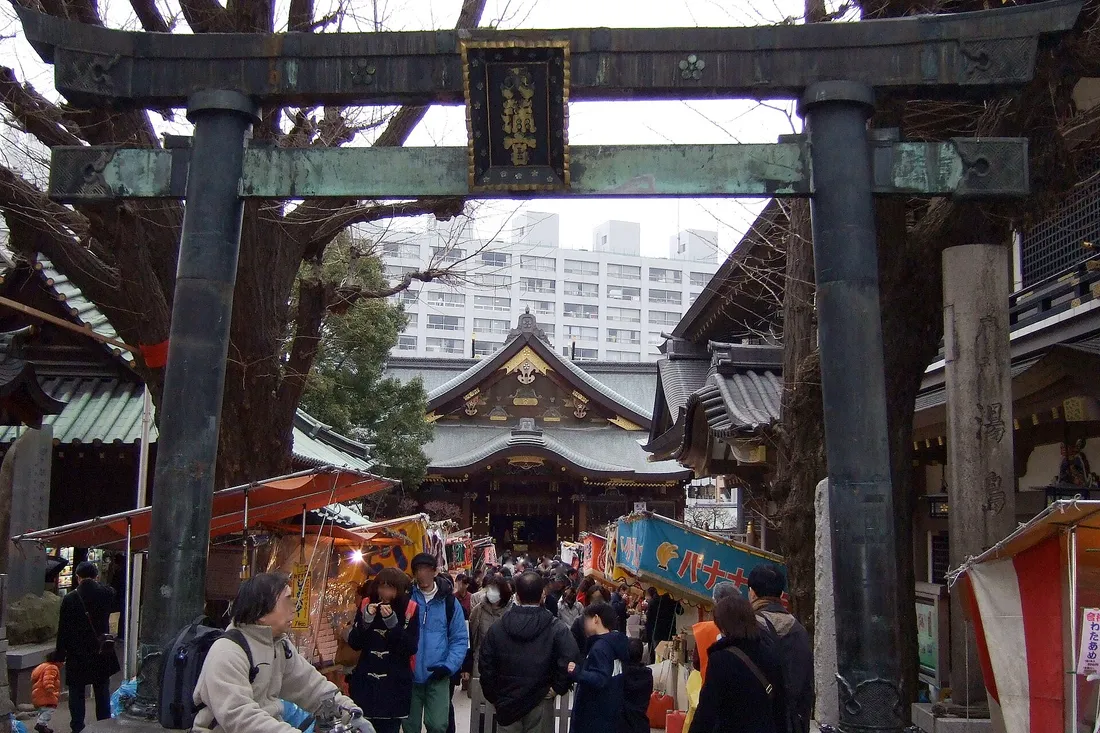 The bronze torii of Yushima Tenjin during the plum festival, with stalls and crowds